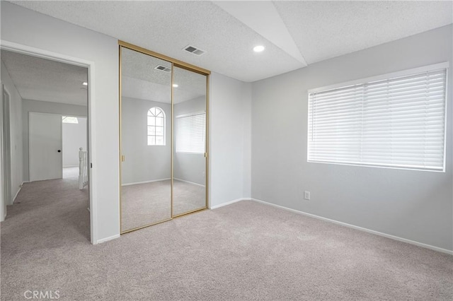 unfurnished bedroom featuring baseboards, carpet, visible vents, and a textured ceiling