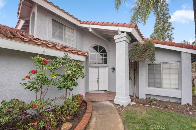 entrance to property with a tile roof and stucco siding