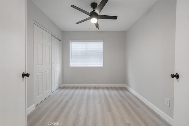 unfurnished bedroom with light wood-type flooring, ceiling fan, baseboards, and a closet