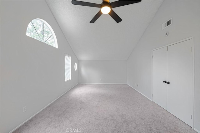 additional living space with visible vents, lofted ceiling, ceiling fan, a textured ceiling, and carpet flooring