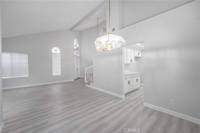 interior space featuring beam ceiling, stairway, an inviting chandelier, light wood-type flooring, and baseboards