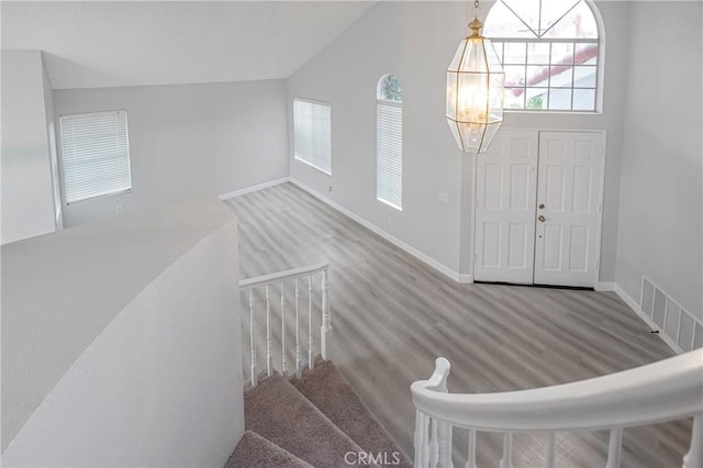 foyer with lofted ceiling, visible vents, and baseboards