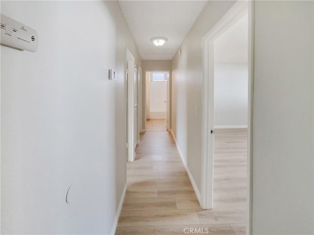 corridor with a wall mounted AC, light wood-style flooring, and baseboards