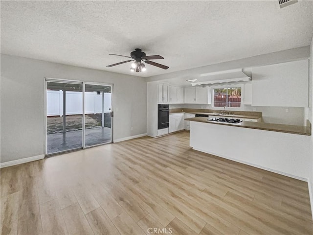 kitchen with a peninsula, light wood-style flooring, oven, and white cabinets