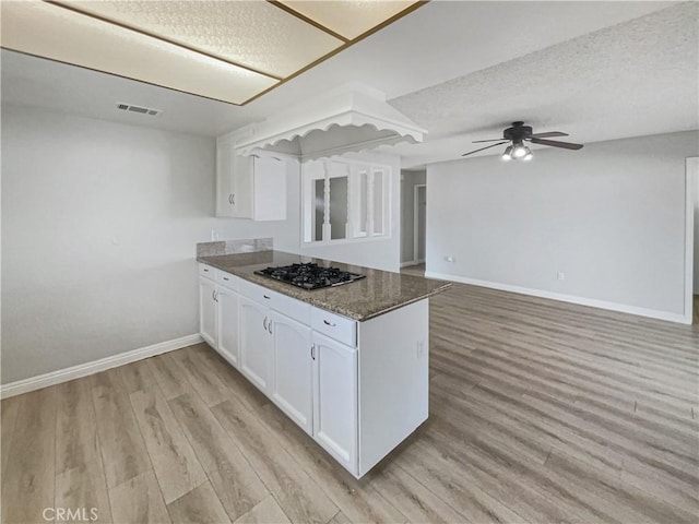 kitchen with a peninsula, black gas stovetop, light wood-style floors, and white cabinets