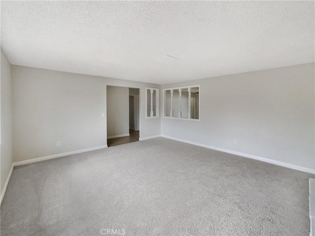 carpeted empty room featuring a textured ceiling and baseboards