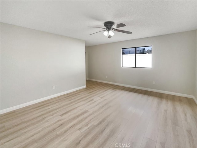 spare room featuring light wood-style floors, ceiling fan, baseboards, and a textured ceiling