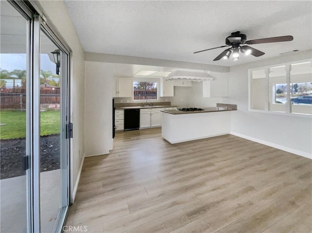 kitchen featuring light wood-style floors, white cabinets, a sink, dishwasher, and a peninsula