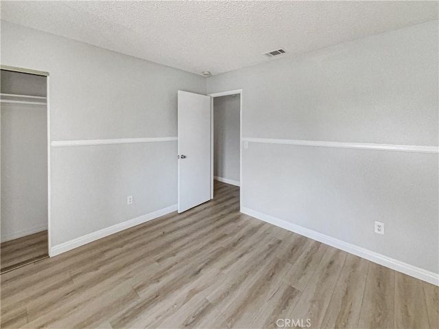 unfurnished bedroom with a textured ceiling, a closet, and wood finished floors