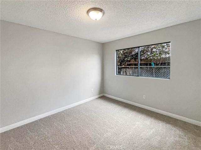 carpeted empty room with a textured ceiling and baseboards