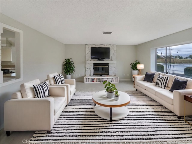 living room featuring visible vents, a textured ceiling, carpet flooring, and a premium fireplace