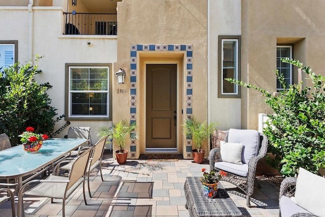 view of exterior entry with a patio area, outdoor dining space, and stucco siding