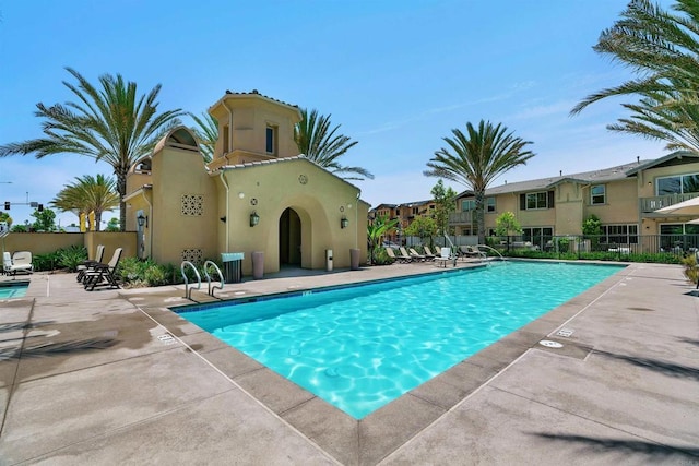 community pool with fence and a patio