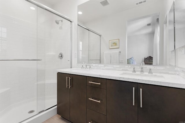 bathroom with a stall shower, visible vents, a sink, and double vanity