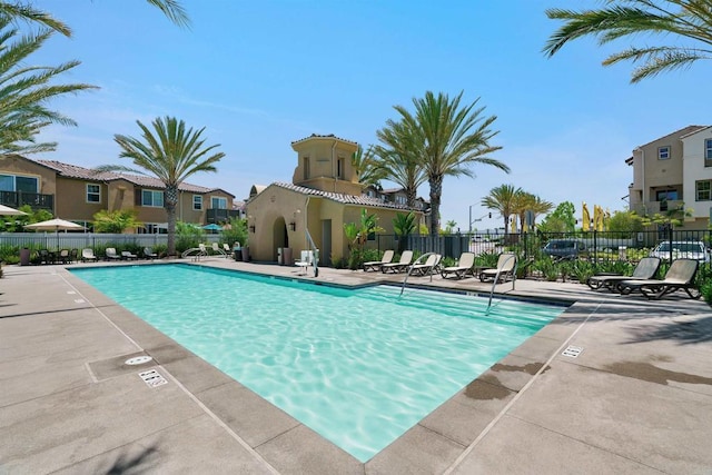 community pool featuring a patio area, fence, and a residential view