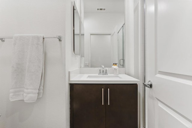 bathroom with visible vents, vanity, and a shower stall