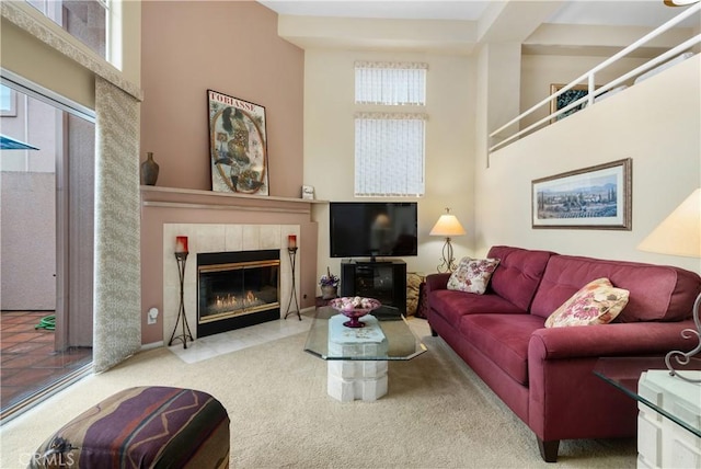 living area featuring carpet floors, a high ceiling, and a tile fireplace