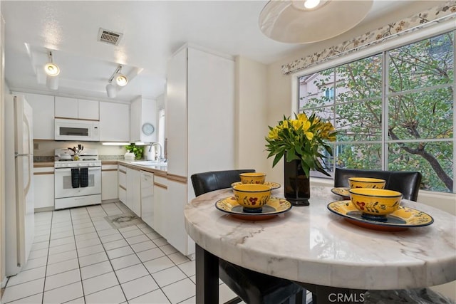 kitchen with light tile patterned floors, white appliances, a sink, visible vents, and white cabinetry