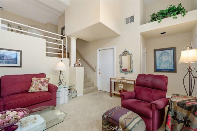 carpeted living area featuring a towering ceiling, stairs, and visible vents