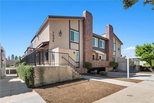 townhome / multi-family property with stucco siding and a chimney