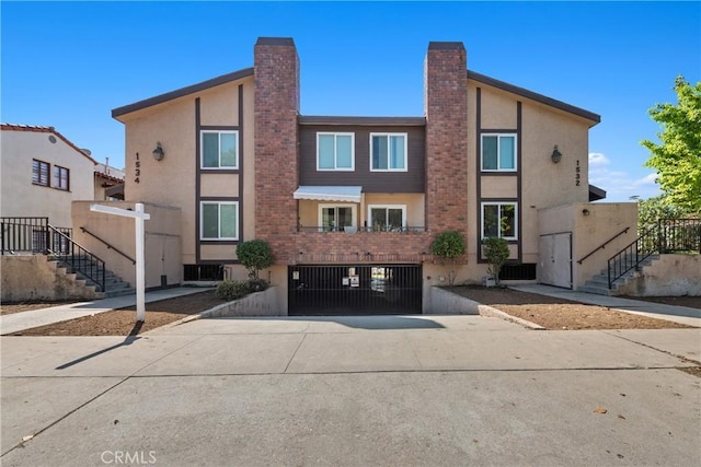 view of property with stucco siding, an attached garage, central AC unit, and driveway