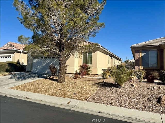 view of front of house featuring a garage, concrete driveway, a tile roof, and stucco siding