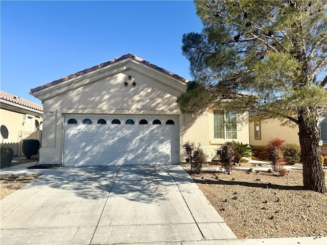 view of front of home featuring a garage, concrete driveway, a tiled roof, and stucco siding