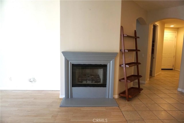 room details with arched walkways, wood finished floors, a glass covered fireplace, and baseboards