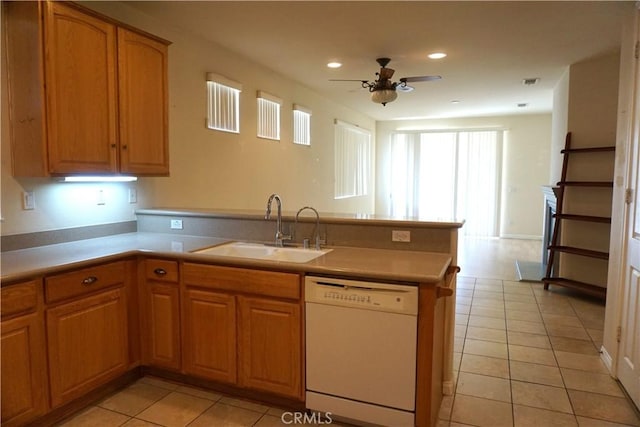 kitchen with dishwasher, a peninsula, a sink, and light tile patterned floors