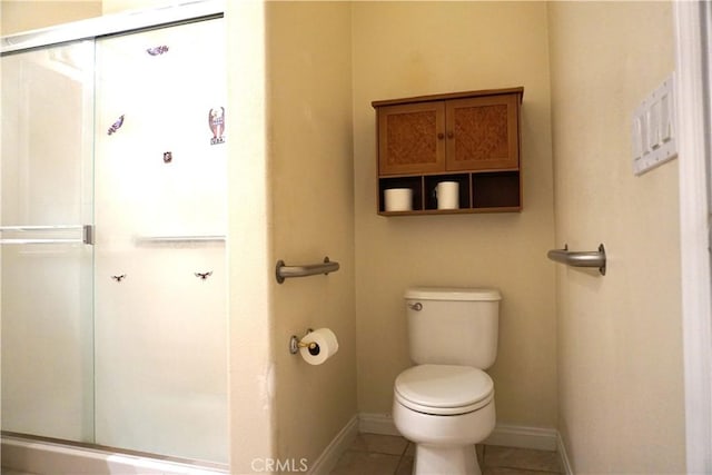 bathroom featuring baseboards, a shower stall, toilet, and tile patterned floors