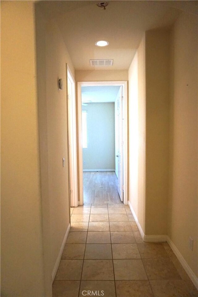 hall featuring visible vents, baseboards, and tile patterned floors