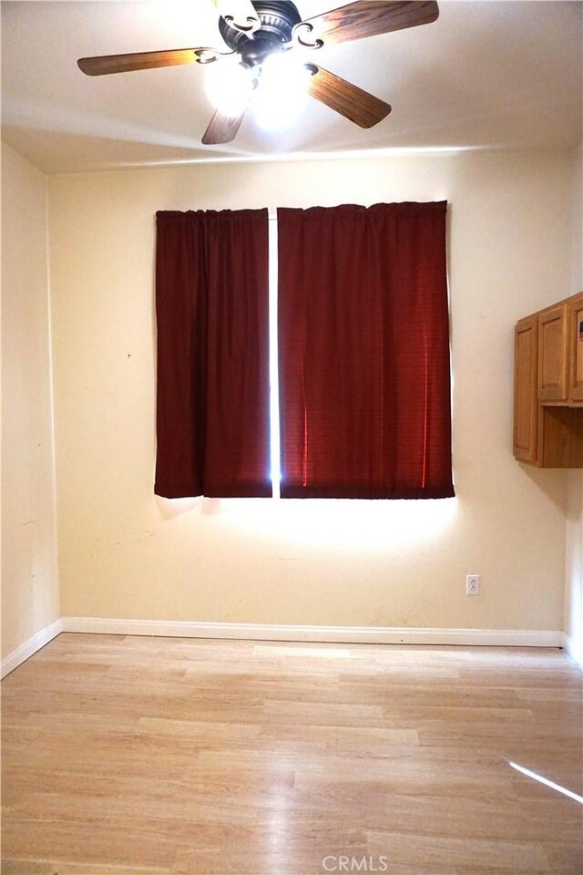 spare room featuring light wood-type flooring and baseboards