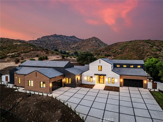 modern farmhouse with stucco siding, driveway, an attached garage, and a mountain view