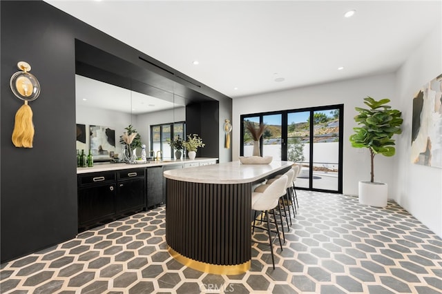 kitchen with a breakfast bar, light countertops, a wealth of natural light, and dark cabinetry