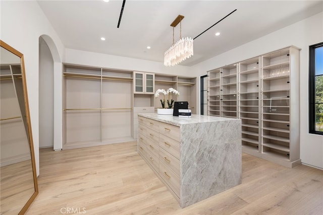 spacious closet featuring arched walkways and light wood-style flooring