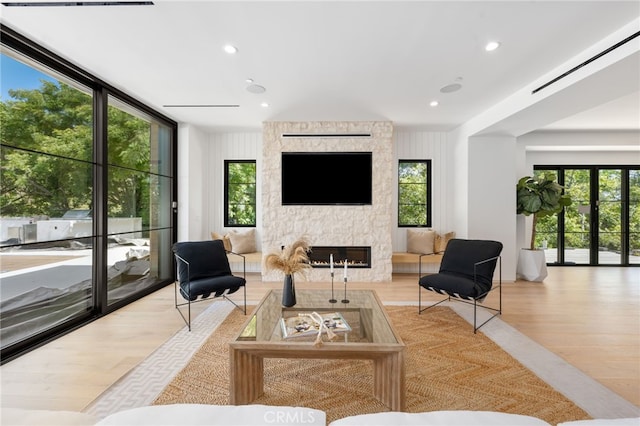 living area featuring french doors, a stone fireplace, wood finished floors, and recessed lighting