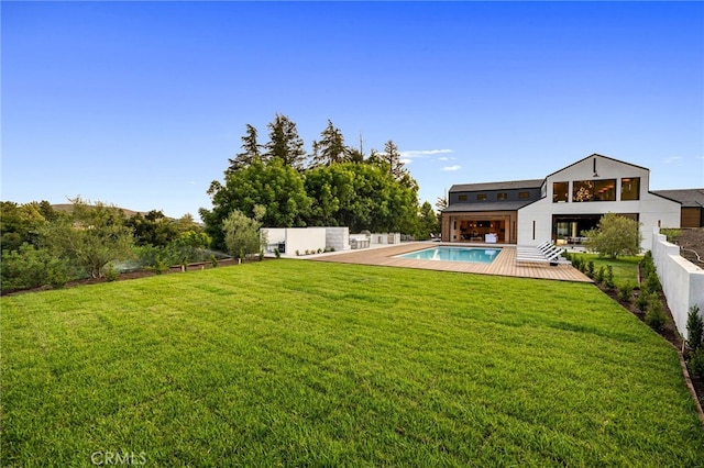view of yard featuring an outdoor pool, a deck, and fence