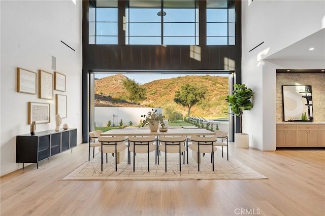 dining space featuring wood finished floors and a towering ceiling
