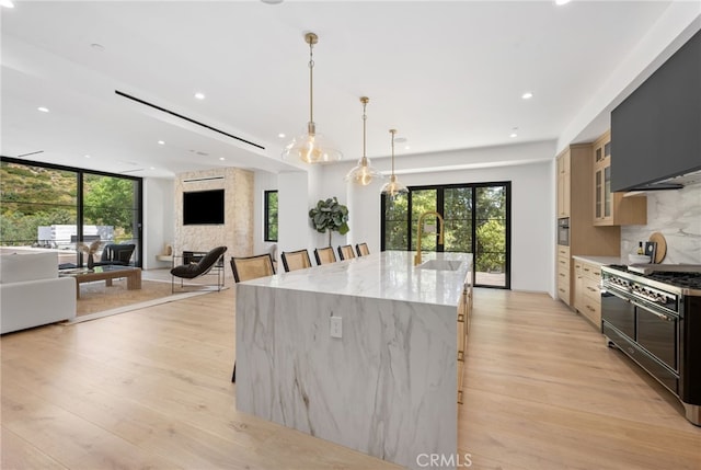 kitchen featuring a spacious island, light wood-style flooring, open floor plan, a sink, and double oven range
