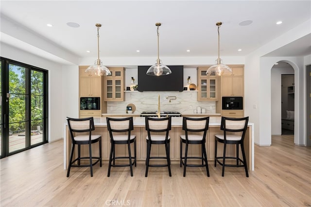 kitchen with arched walkways, light countertops, ventilation hood, and light brown cabinets