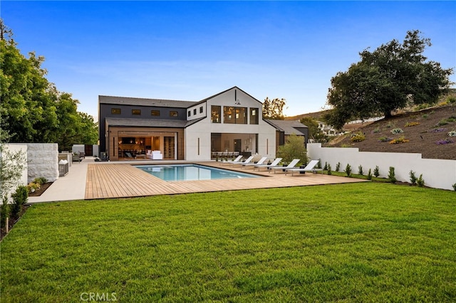 rear view of property with a fenced in pool, fence, a lawn, and a patio