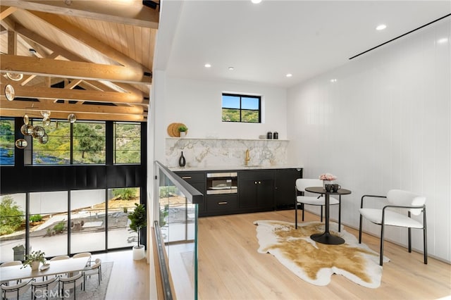bar featuring vaulted ceiling with beams, light wood-style flooring, and bar area