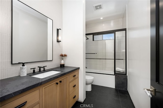 bathroom with bath / shower combo with glass door, visible vents, toilet, vanity, and tile patterned floors