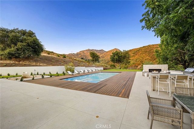 view of swimming pool featuring a patio, area for grilling, a mountain view, and a fenced in pool