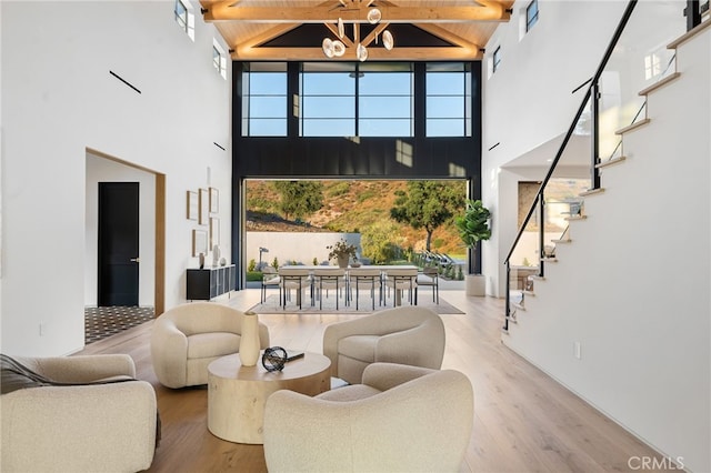 living area featuring high vaulted ceiling, stairway, wood finished floors, and beamed ceiling