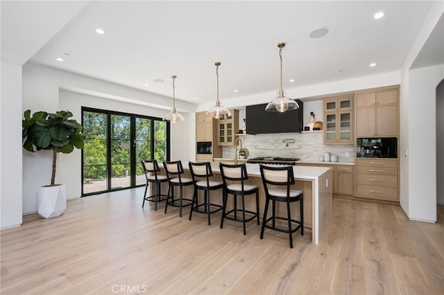 kitchen with a kitchen breakfast bar, light wood-style floors, light countertops, a large island, and tasteful backsplash