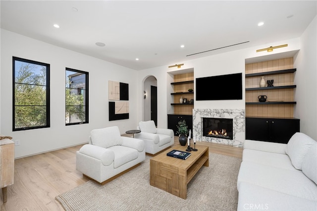 living area with built in shelves, a fireplace, wood finished floors, and recessed lighting