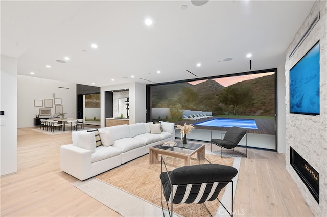 living area with a stone fireplace, wood finished floors, and recessed lighting