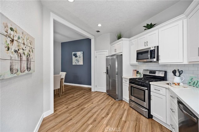 kitchen with stainless steel appliances, light countertops, light wood-style flooring, and tasteful backsplash