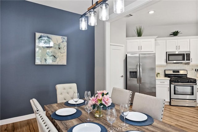 dining space featuring wood finished floors, visible vents, and baseboards